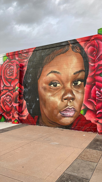 Photograph of a mural of Breonna Taylor surrounded by roses