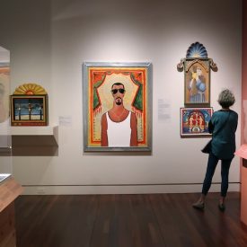 A woman views art pieces hanging on the wall in the museum gallery.