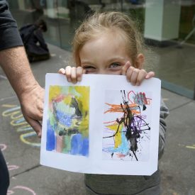 A little girl holds up a card she created at Family Adventure Day