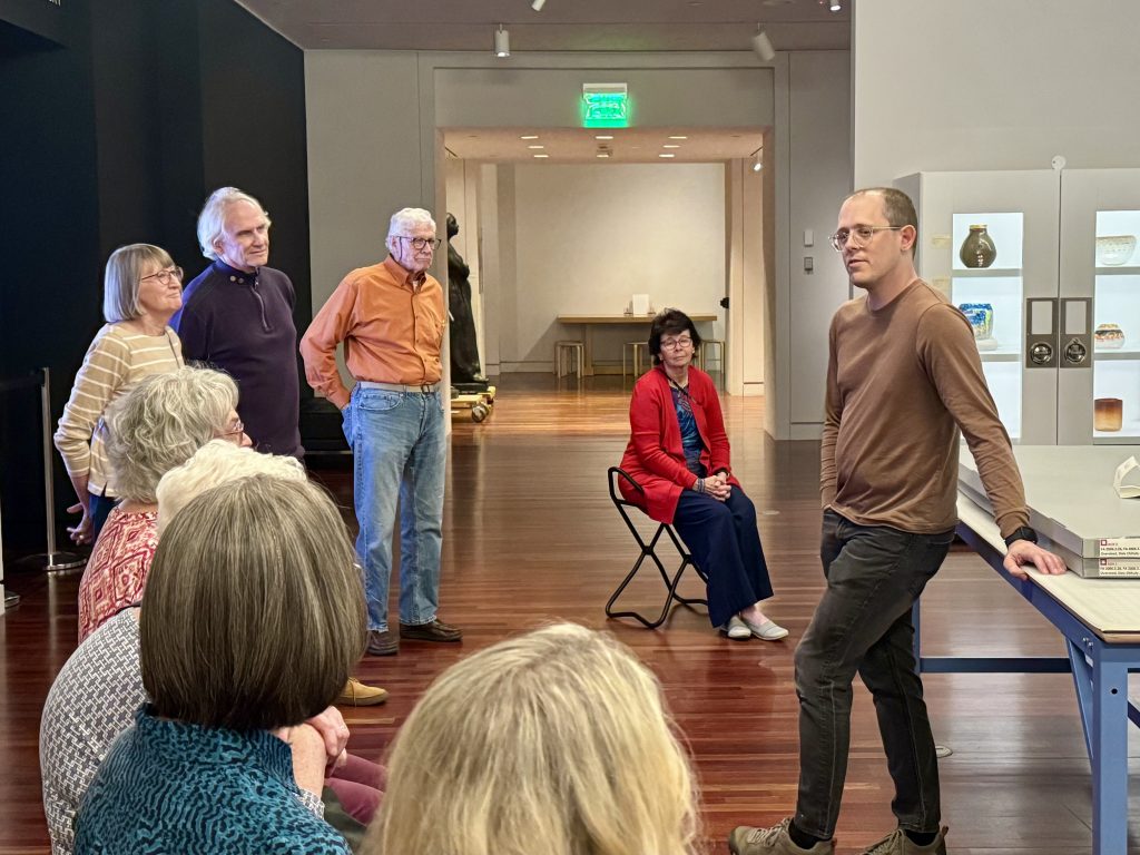 A man speaks to a group of museum members in an exhibit hall