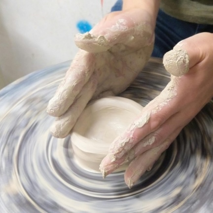 Someone throwing some clay on a pottery wheel