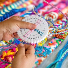 someone creates colorful braided cords with a disk loom