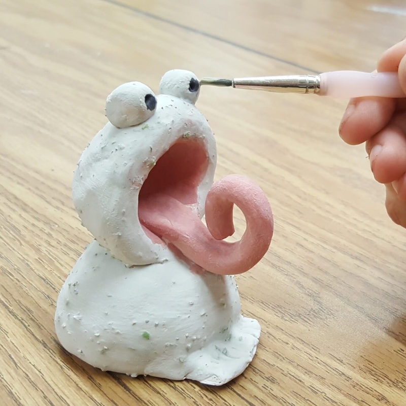 A white clay lizard with a pink tongue.