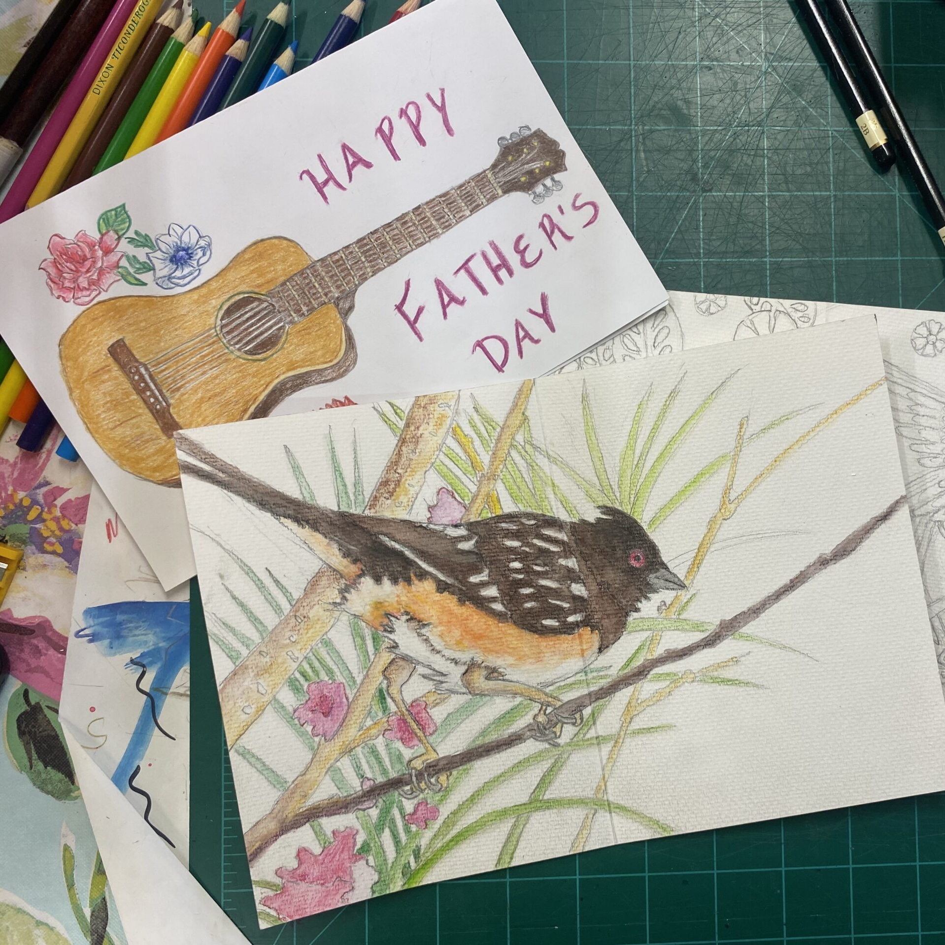 two hand drawn and colored greeting cards. One says "Happy Father's Day" and has a guitar. One has a bird perched on a branch