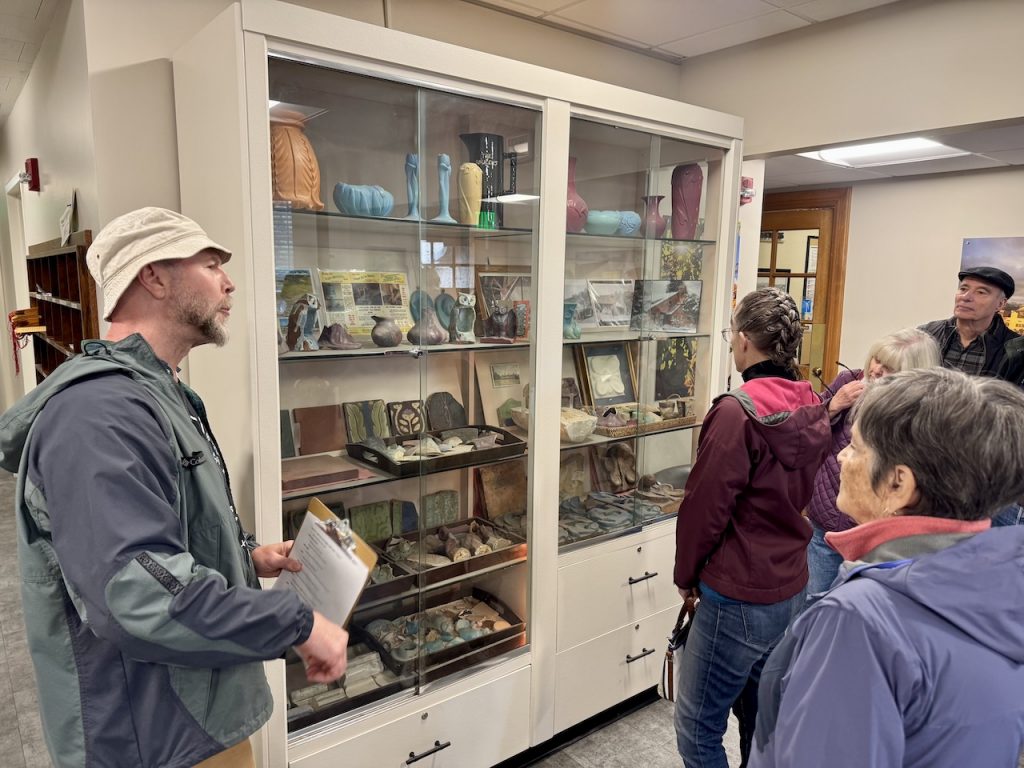 members look at pottery pieces in a display case