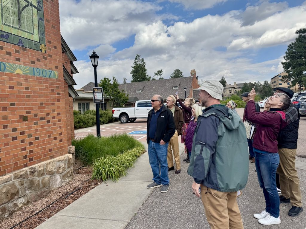 members stand outside and look at pottery details on the Van Briggle building