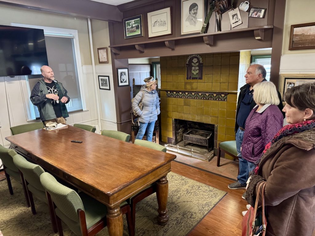 members stand looking at pottery detailing on a fireplace surround in the Van Briggle building