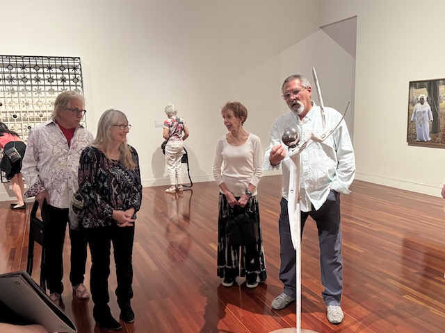 Members look at an art piece made from bleached antlers and a silver globe