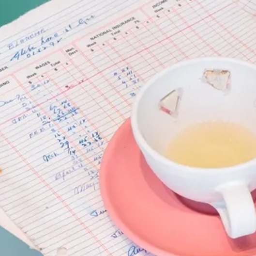 tea cup on pink saucer sitting on what appears to be a handwritten accounting document