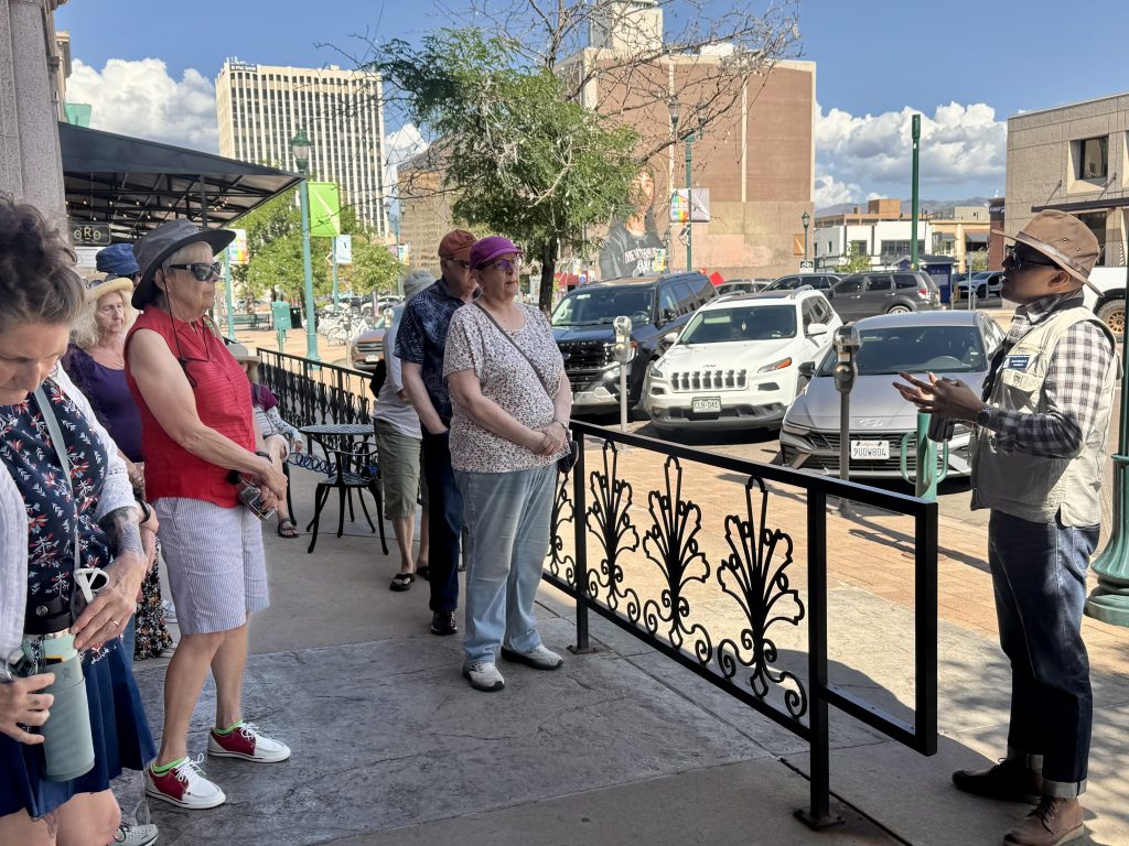 tour guide talks to group of members on a sidewalk downtown
