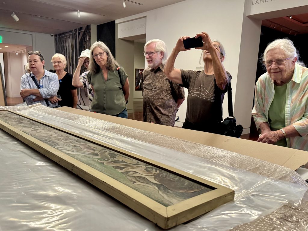 Members look at an unboxed Mechau piece on a display table