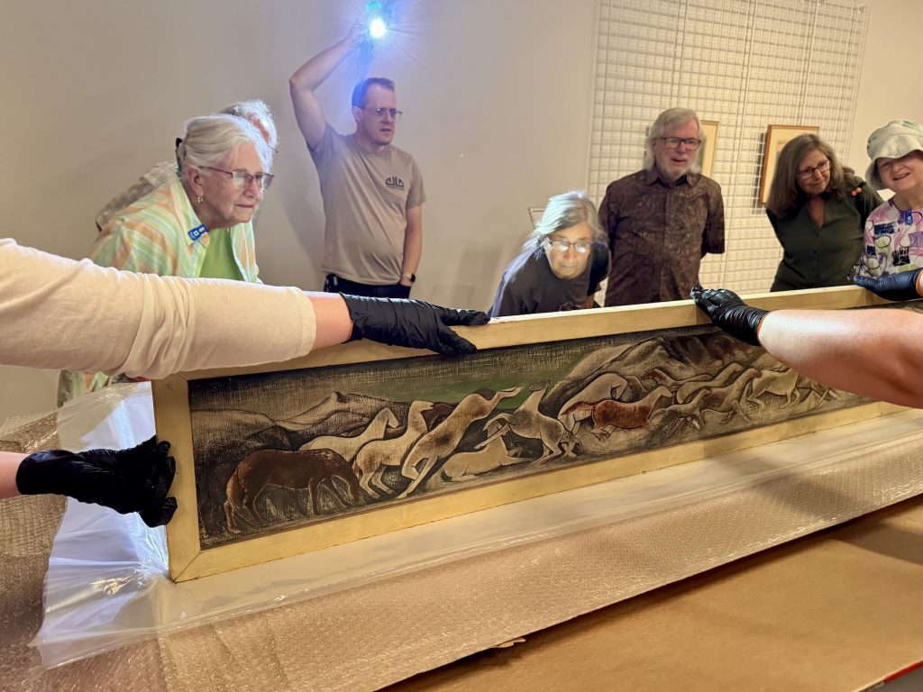 Members look at an unboxed Mechau piece on a display table